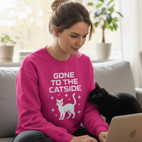Load image into Gallery viewer, Woman wearing a pink sweatshirt with a cat design and text, sitting on a couch with a laptop.
