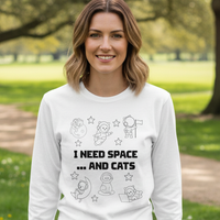 Load image into Gallery viewer, Woman wearing a white sweatshirt with text and graphics, sitting on a bench in a park.